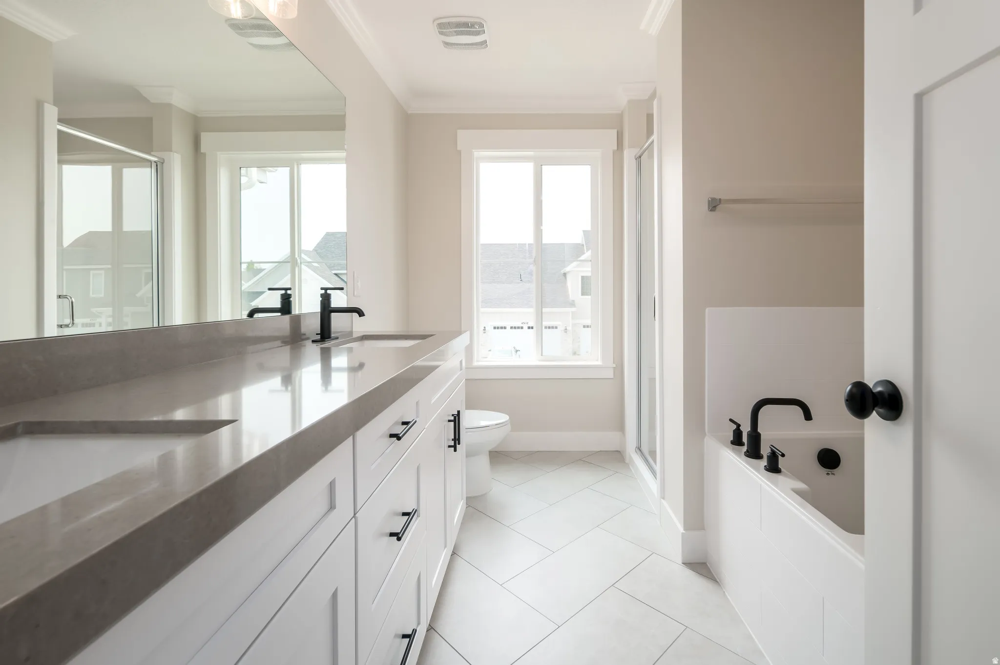 Contemporary bathroom featuring a double vanity with integrated sinks, a large mirror, and matte black fixtures