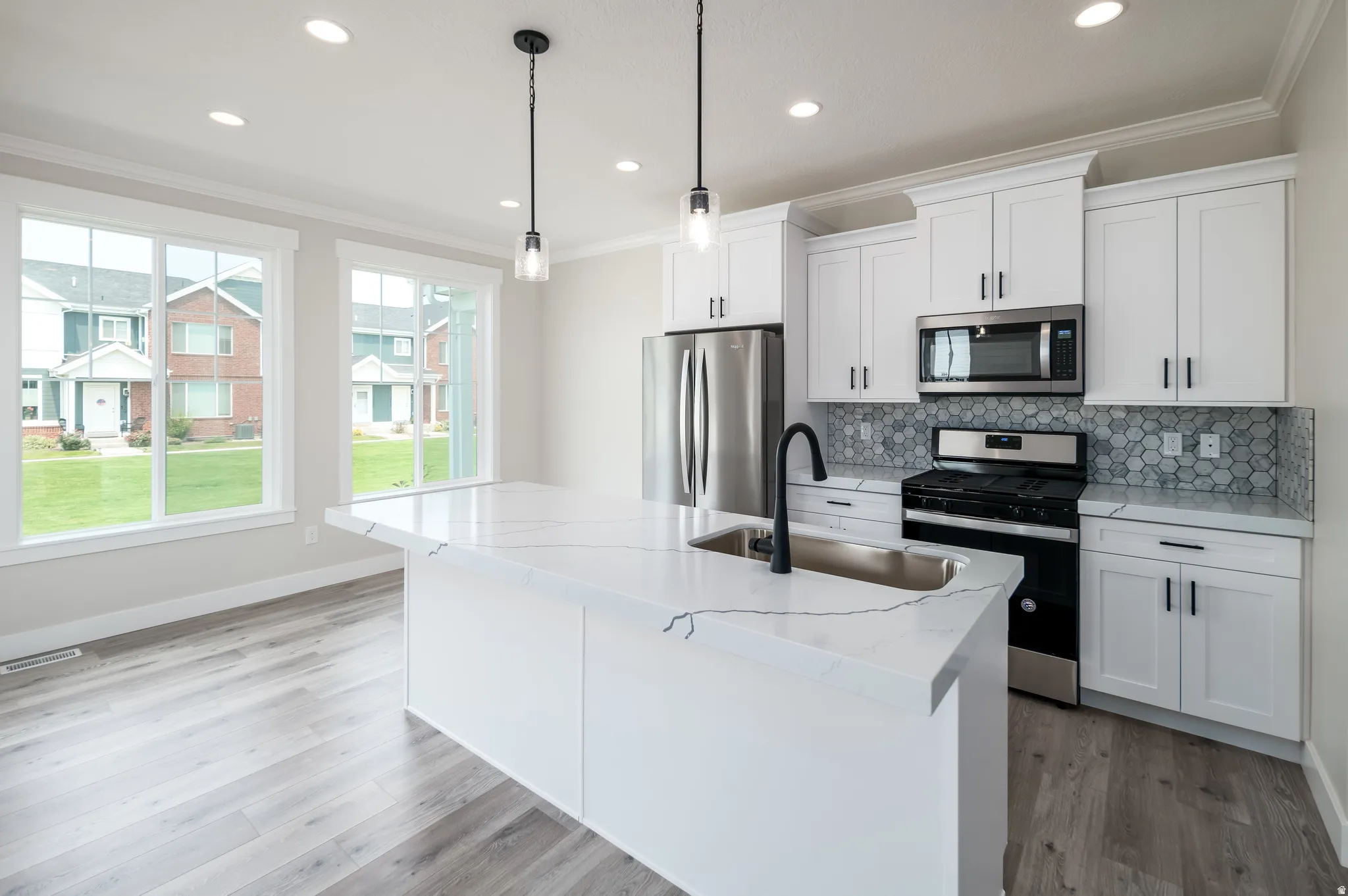Modern kitchen featuring white cabinetry, stainless steel appliances, and a hexagonal tile backsplash