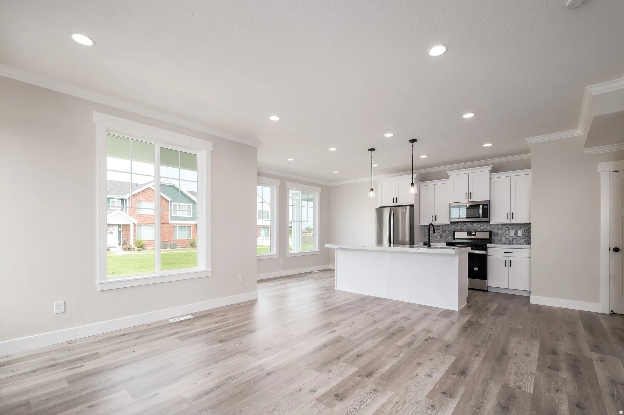Open-concept living area featuring wood-finish flooring, recessed lighting, and multiple windows