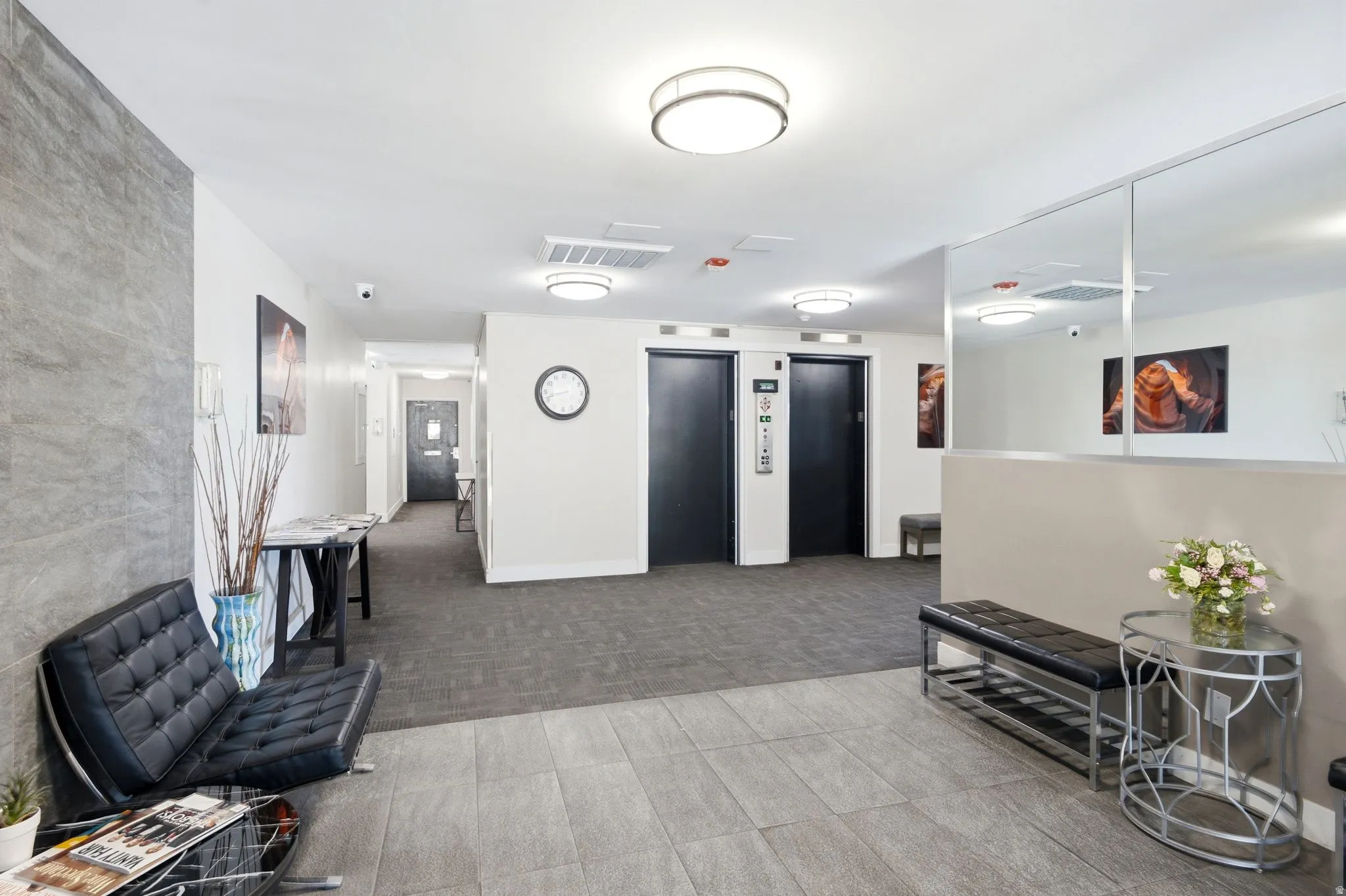 Lobby area featuring tile flooring, two elevators, a mirrored wall, and a textured accent wall