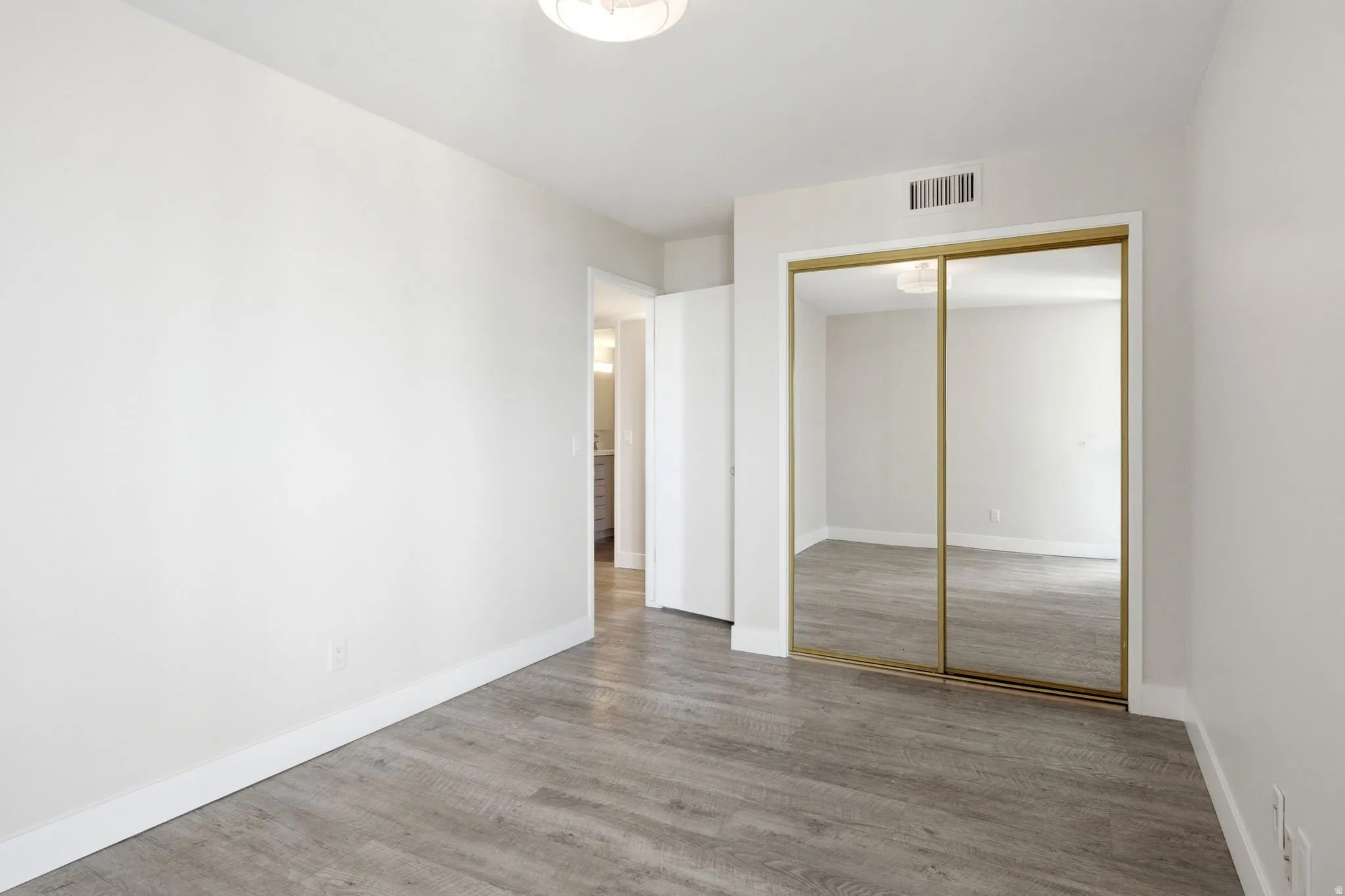 Bright interior space featuring wood-finish flooring, white walls, and a recessed ceiling light