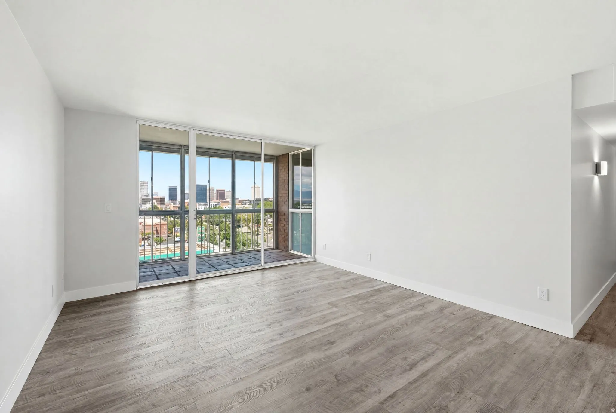 Spacious room featuring wood-finish flooring, white baseboards, and a sliding glass door opening to a private balcony