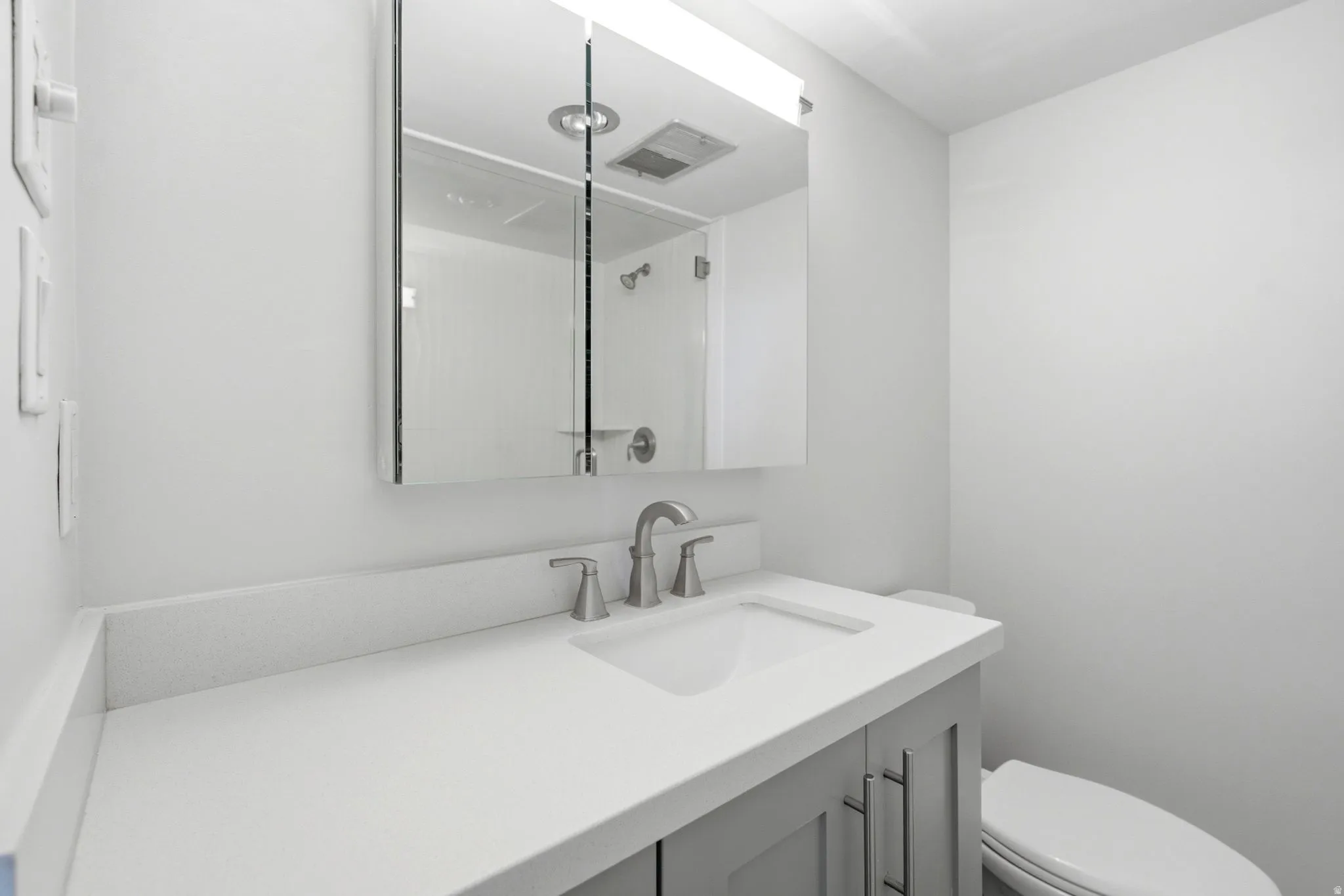 Bathroom vanity featuring a light gray base cabinet, white countertop, and brushed nickel faucet