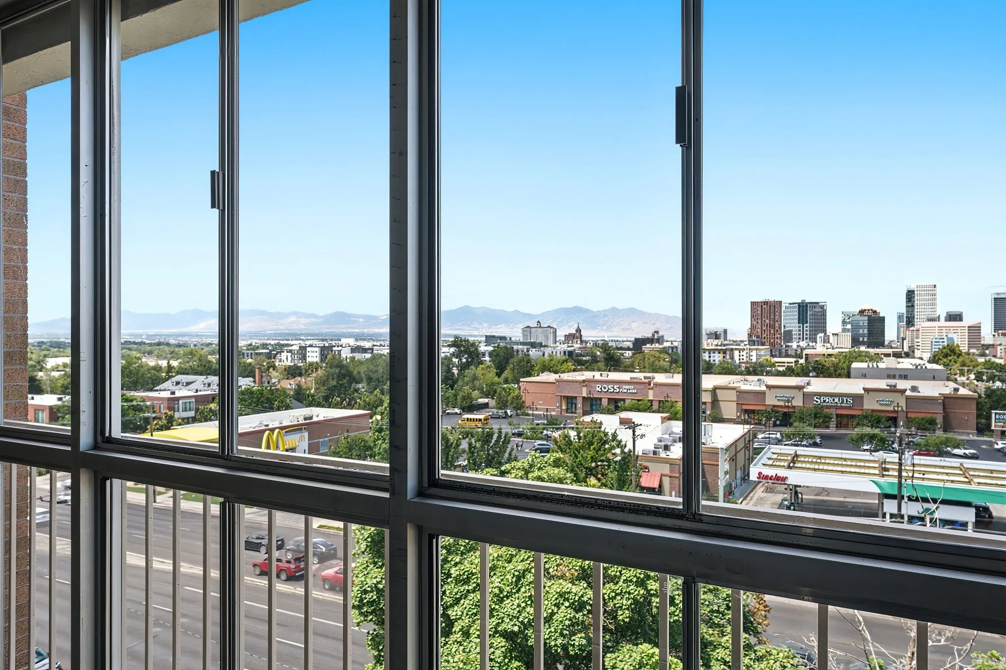 Expansive window wall with dark framing, offering urban and distant mountain scenery
