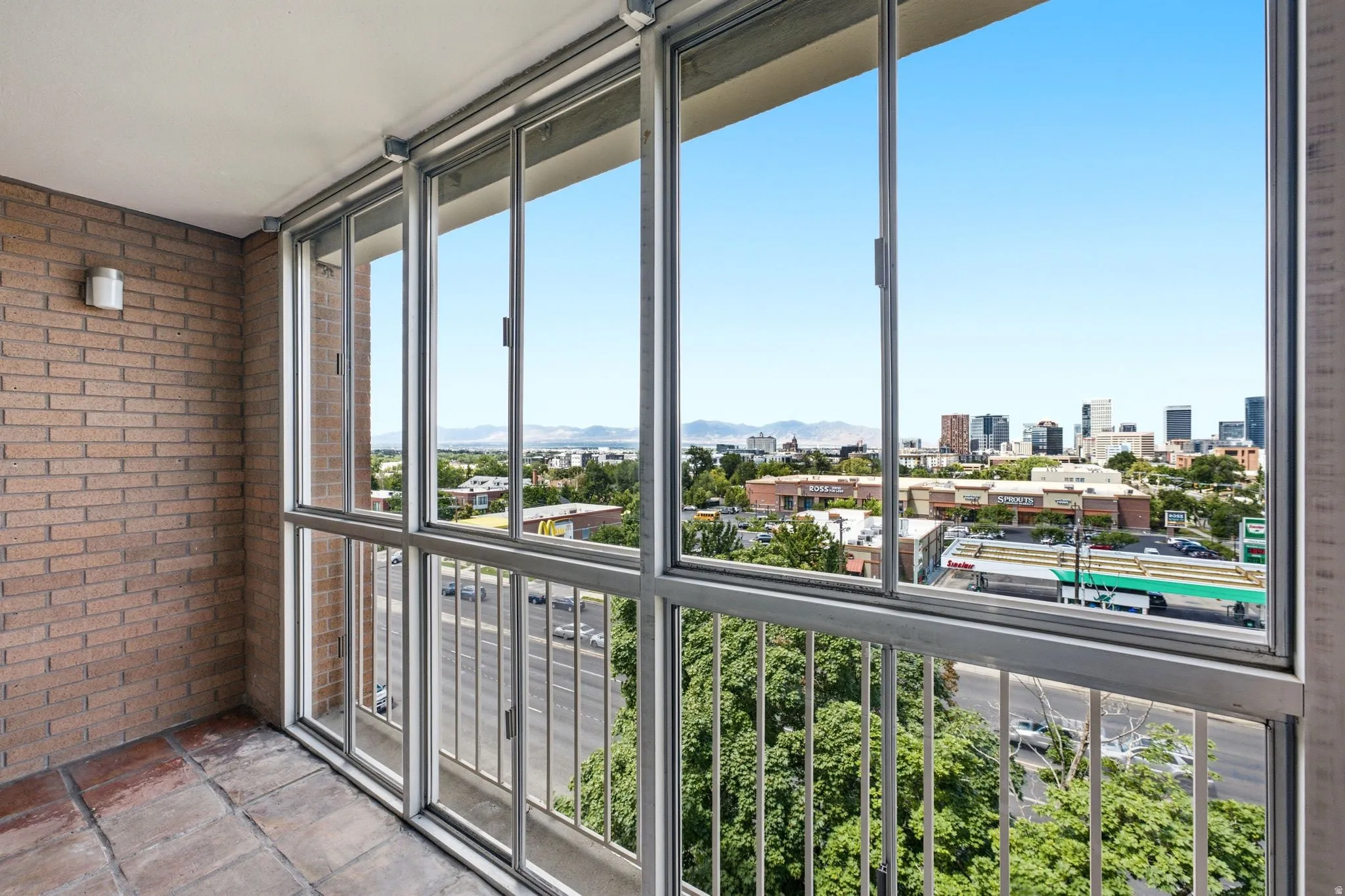 Enclosed balcony featuring brick wall, terracotta-style flooring, and large windows