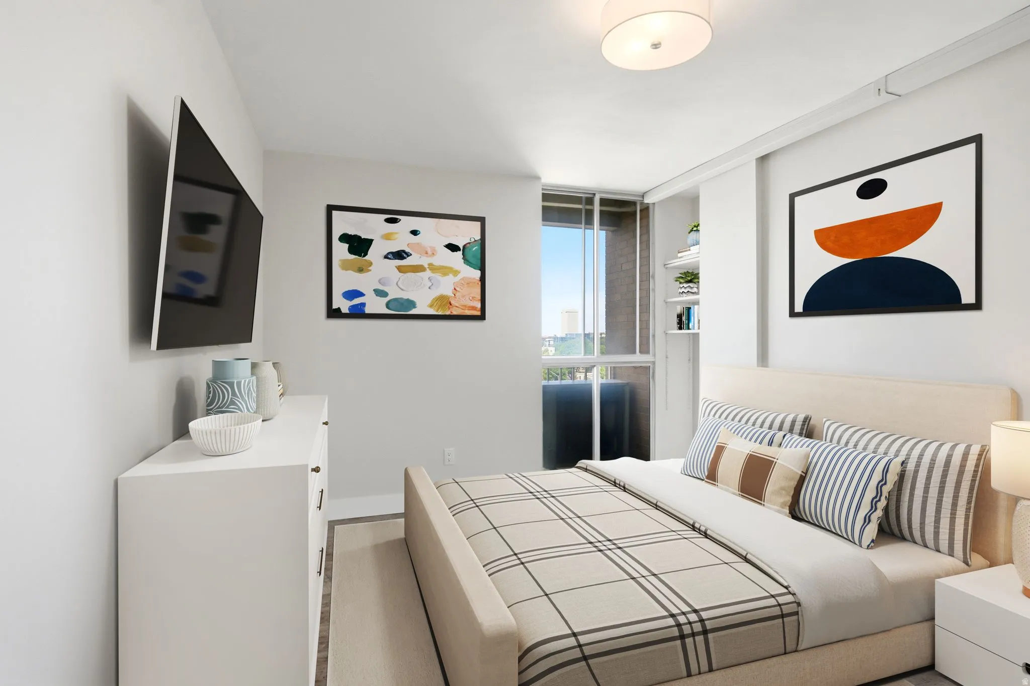 Bright bedroom with a full-height window, built-in shelving, wood-finish flooring, a wall-mounted television, and a flush-mount ceiling light fixture