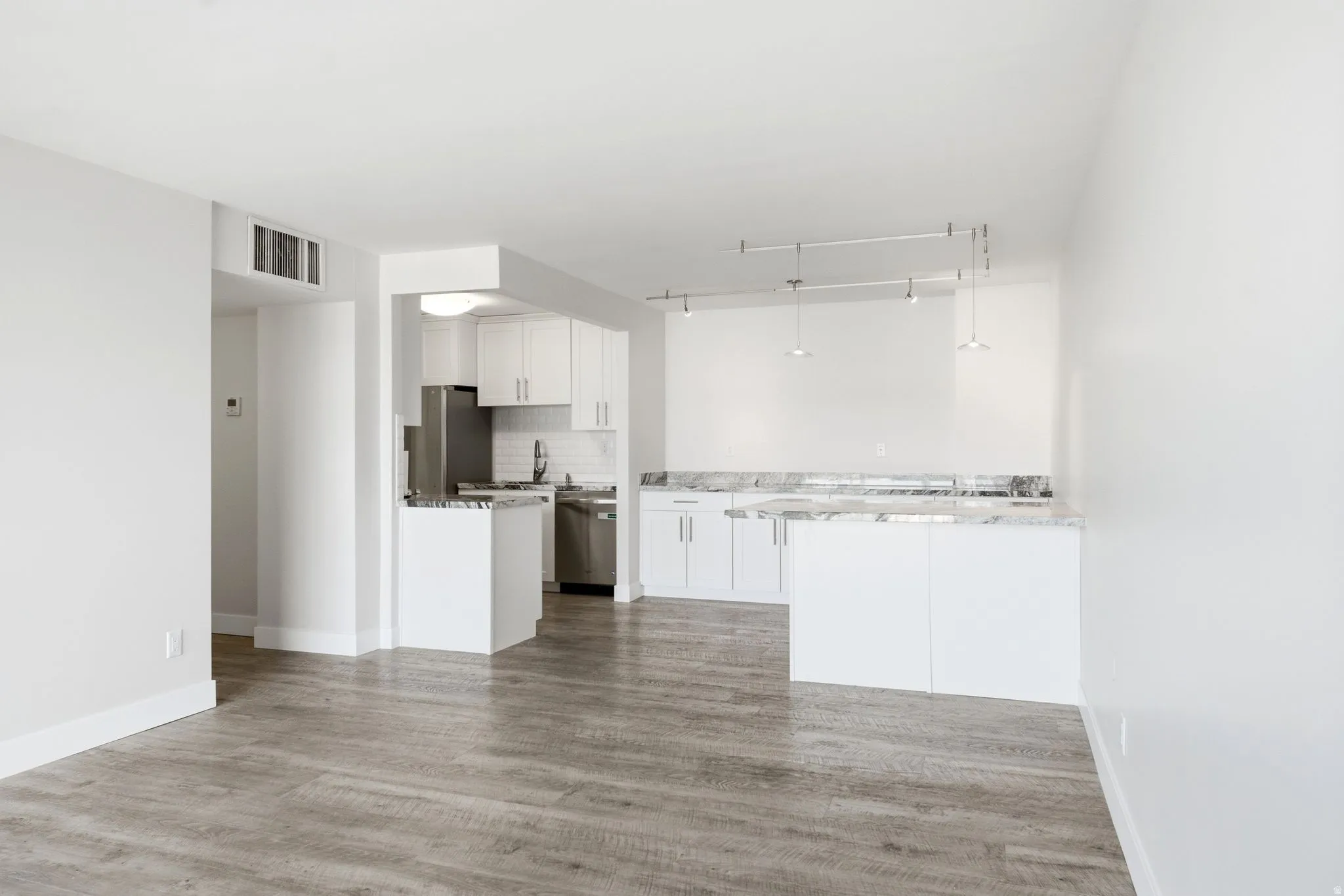 Open-concept living space featuring wood-finish flooring, white walls, and track lighting