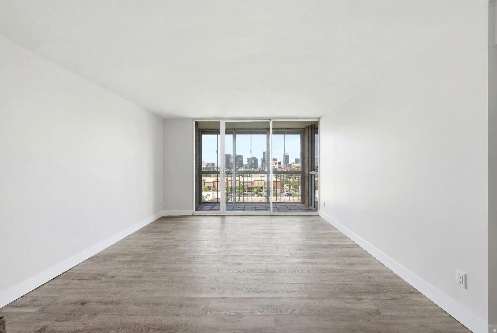 Spacious room featuring light wood-finish flooring and white baseboards