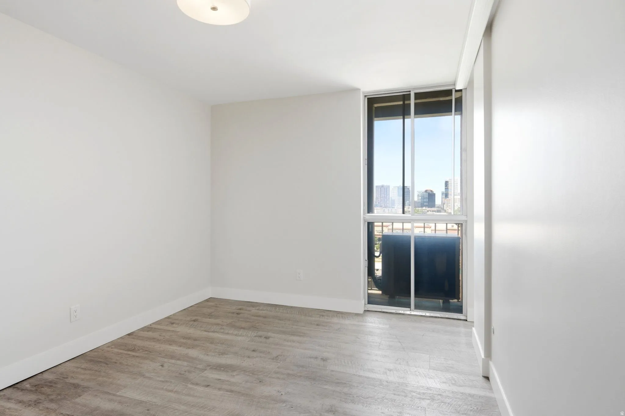 Room featuring wood-finish flooring, white walls, and a contemporary ceiling light fixture
