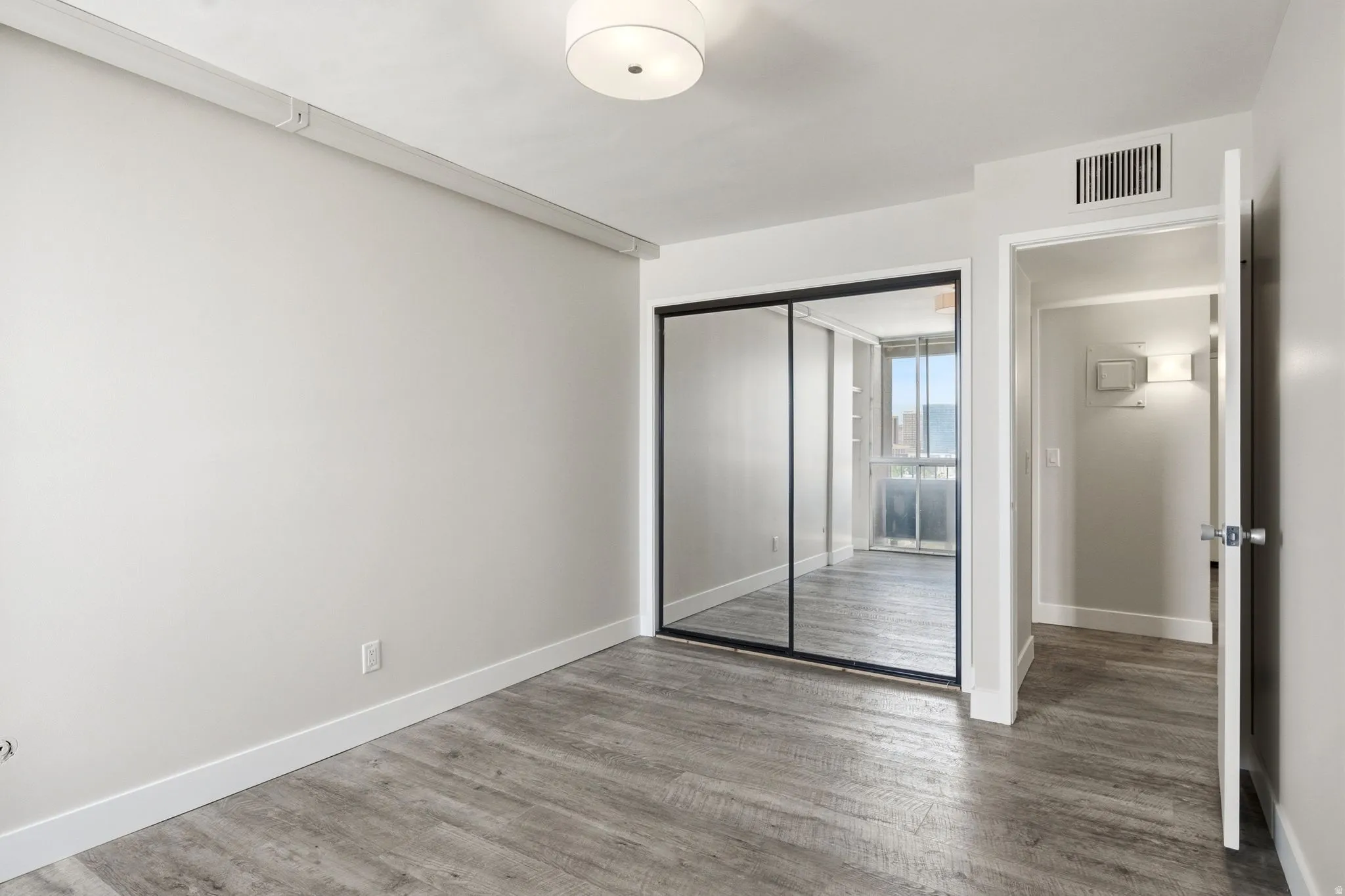 Room featuring wood-finish flooring, light grey wall paint, and white baseboards