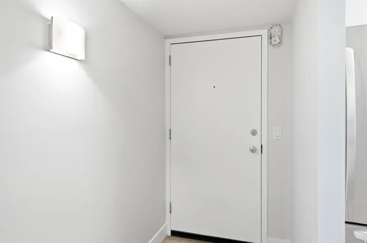 White entry door with satin nickel hardware and a wall-mounted sconce