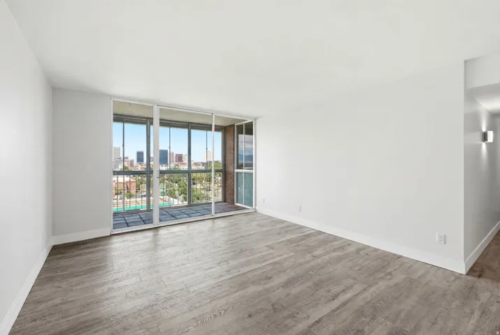 Spacious room featuring wood-finish flooring, white baseboards, and a sliding glass door opening to a private balcony