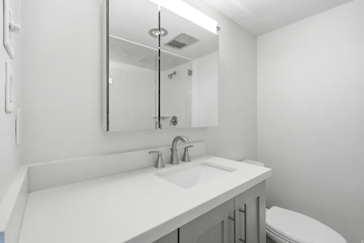 Bathroom vanity featuring a light gray base cabinet, white countertop, and brushed nickel faucet