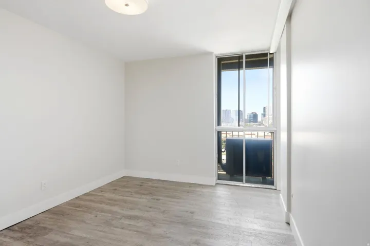 Room featuring wood-finish flooring, white walls, and a contemporary ceiling light fixture