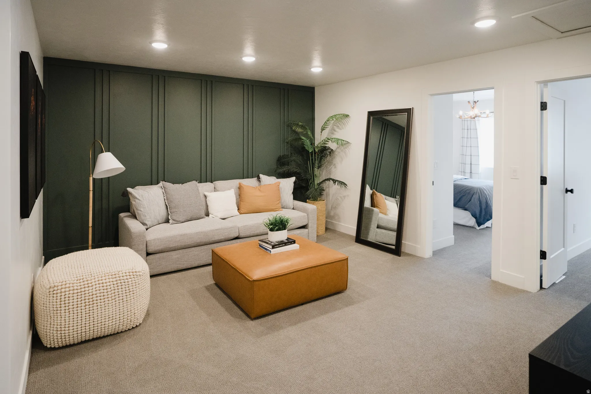 Spacious room featuring a dark green accent wall with vertical paneling, recessed lighting, and light grey carpet