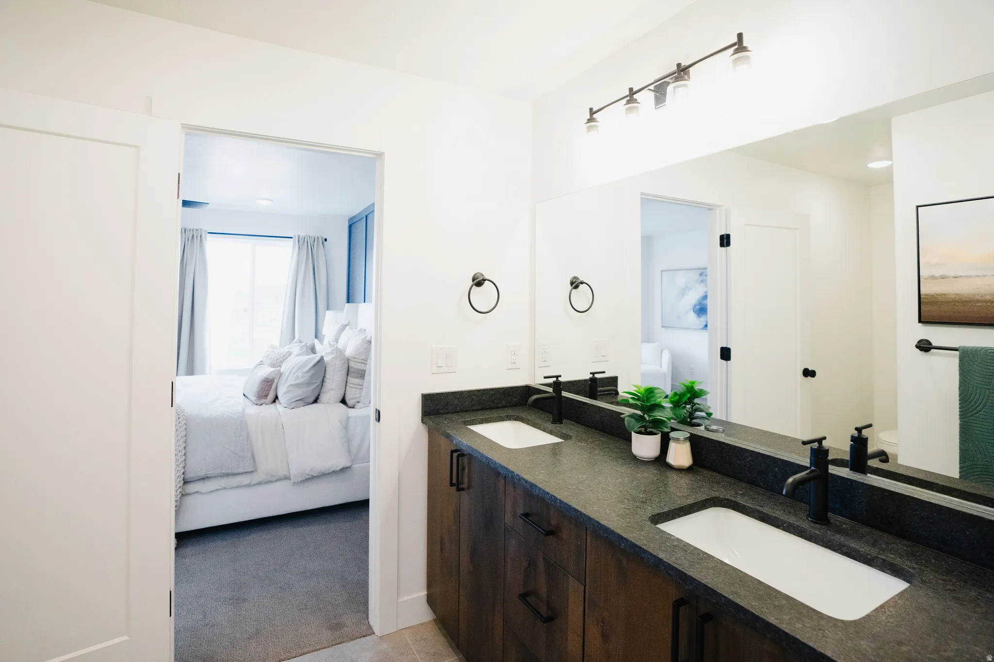 Double vanity with dark wood-finish cabinetry, integrated rectangular sinks, and matte black fixtures