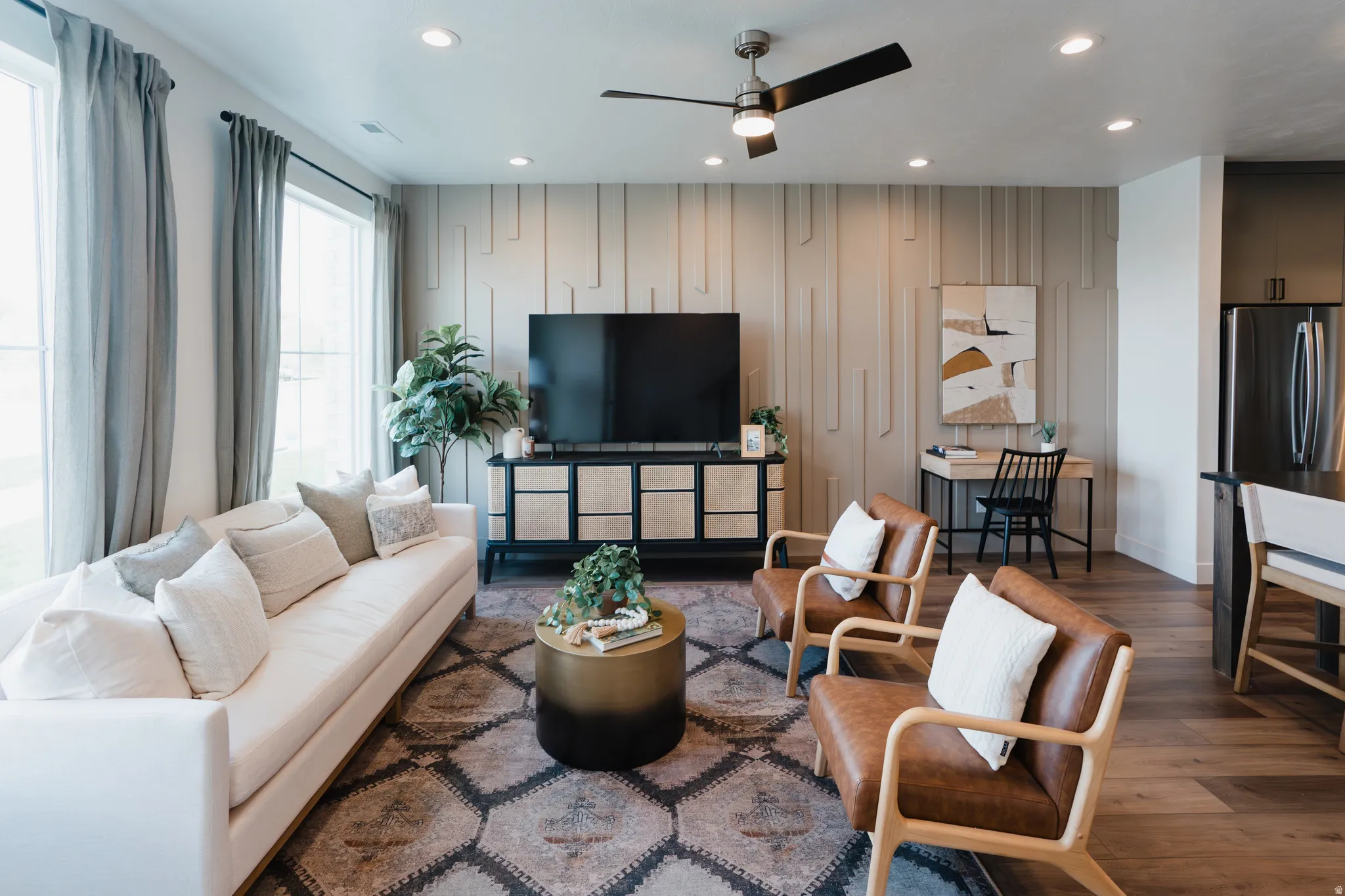 Living area featuring recessed lighting, a modern ceiling fan, wood-finish flooring, and an accent wall with geometric paneling