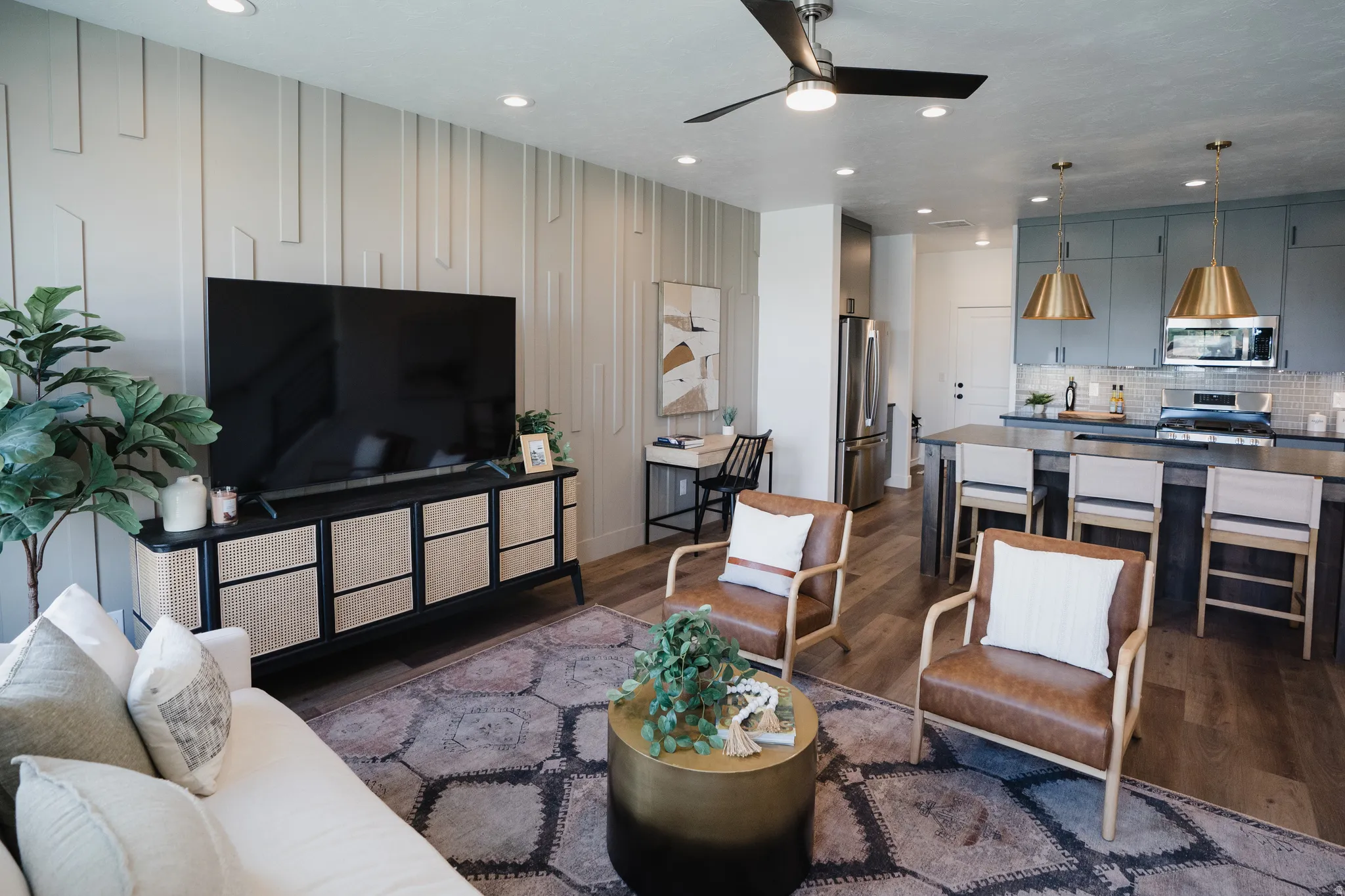 Open-concept living area featuring a decorative accent wall, wood-finish flooring, and recessed lighting