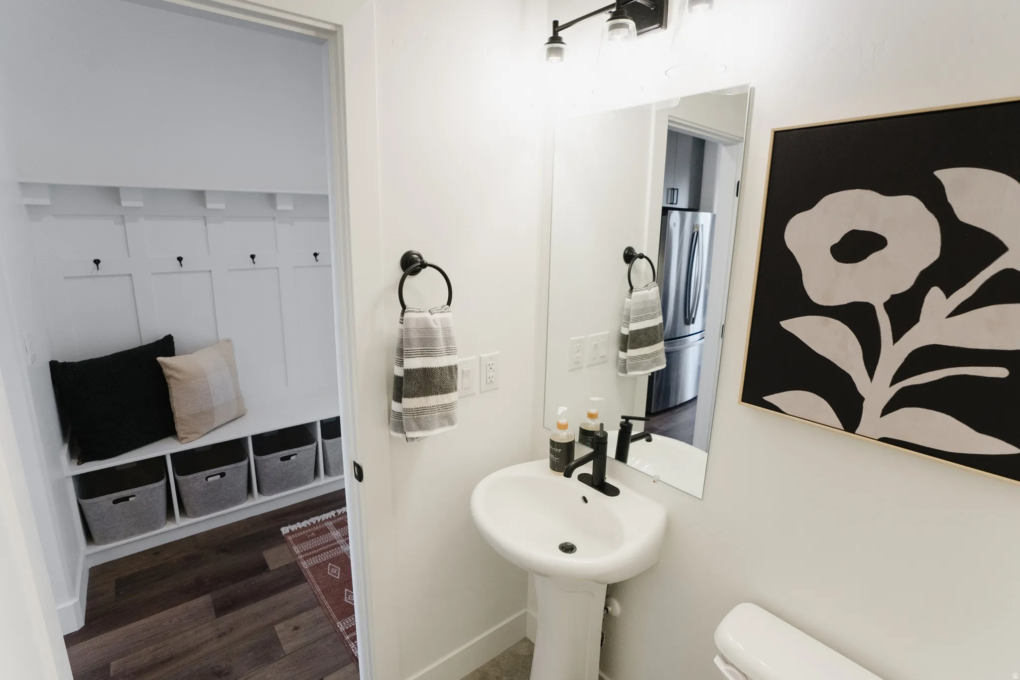 Pedestal sink with matte black faucet and wall-mounted mirror