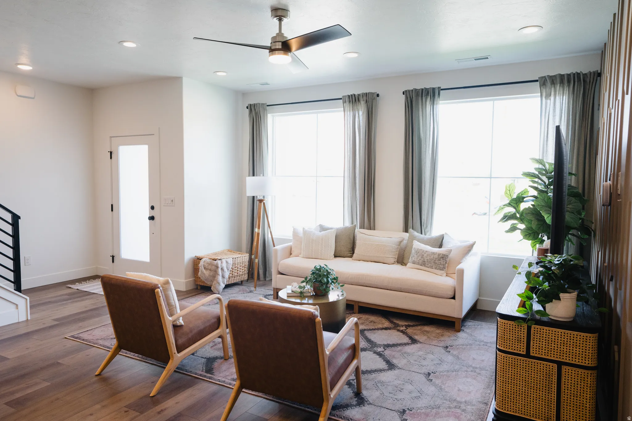 Open-concept living space with wood-finish flooring, recessed lighting, and a contemporary ceiling fan