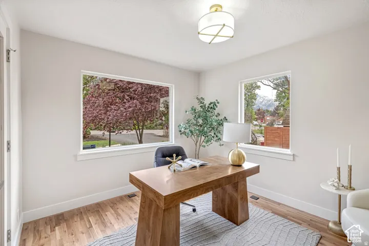 Bright room featuring two large windows, wood-finish flooring, and white baseboards