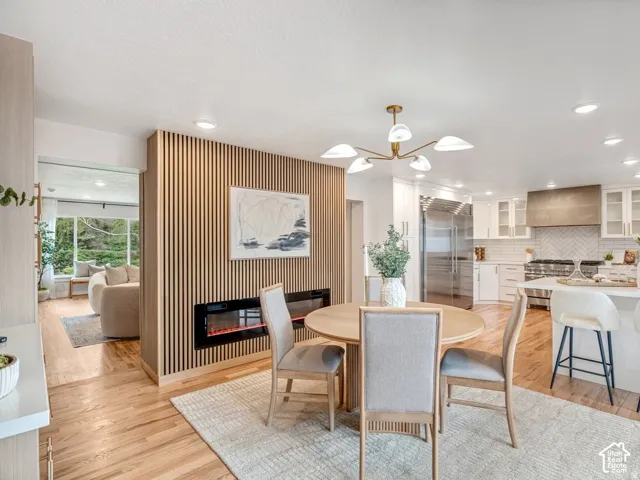 Dining area featuring a contemporary linear fireplace, wood-finish flooring, and a modern light fixture