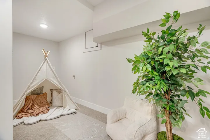 Recessed lighting illuminates a carpeted room featuring white walls and a white baseboard