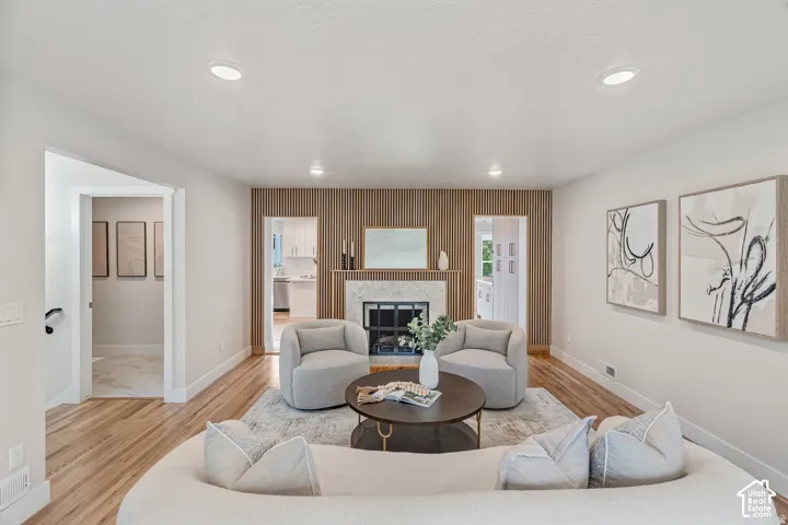 Living area featuring wood-finish flooring, recessed lighting, and a fireplace with a stone surround and wood slat accent wall