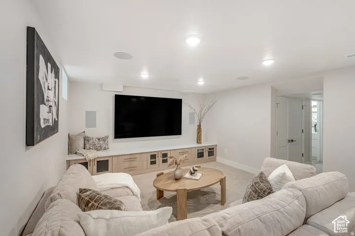 Integrated media wall with built-in cabinetry, flush-mount speakers, recessed lighting, and a neutral carpeted floor