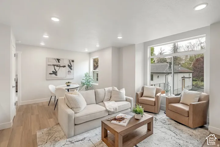 Open-concept living area with recessed lighting, wood-finish flooring, and large picture windows