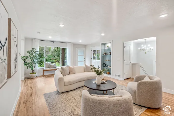 Open-concept living area featuring wood-finish flooring, recessed lighting, and a prominent window with a built-in bench seat