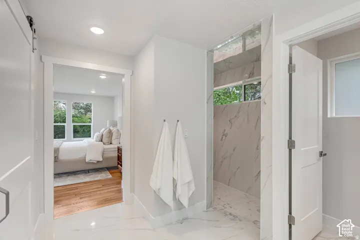 Modern bathroom featuring large format marble-look tile flooring and a spacious walk-in shower with matching wall tile