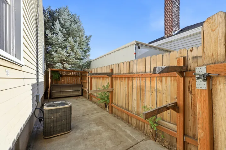 Fenced outdoor area featuring a concrete walkway, wood privacy fencing, and a built-in outdoor storage unit