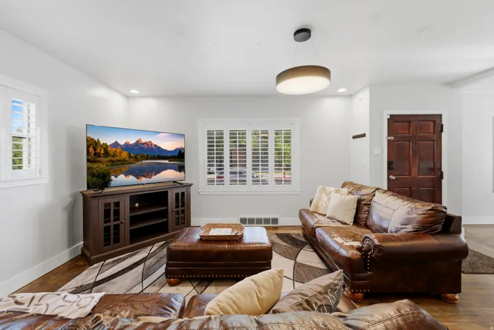 Living space featuring light gray walls, recessed lighting, wood-finish flooring, and white plantation shutters on windows