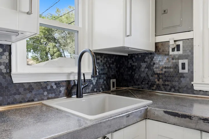 Kitchen featuring concrete countertops, a matte black gooseneck faucet, an undermount sink, and hexagonal tile backsplash