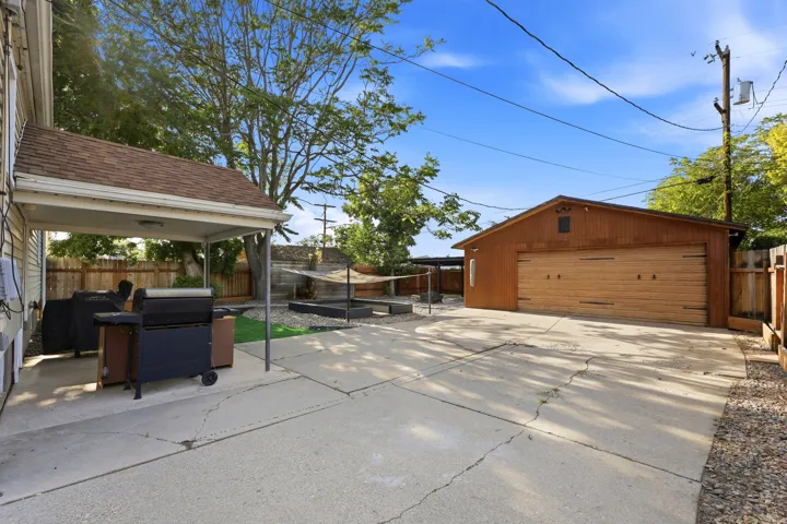 Spacious concrete driveway leading to a detached extra wide two-car garage with wood-finish doors