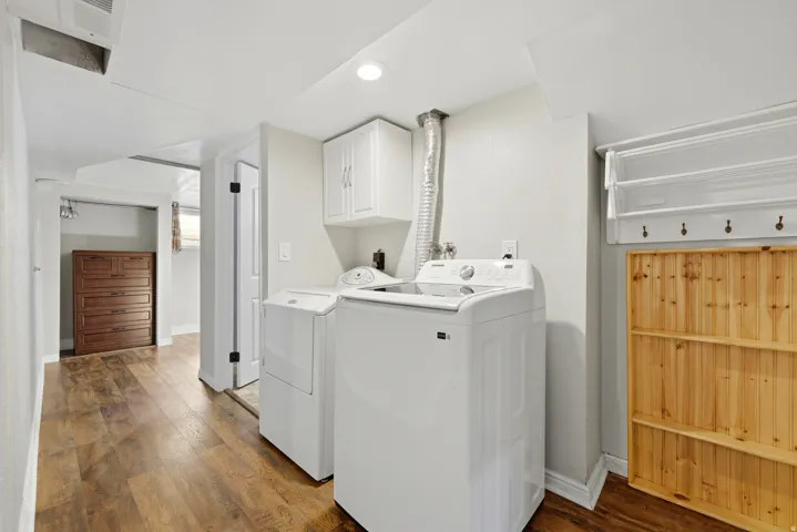 Dedicated laundry area featuring wood-finish flooring, white cabinetry, and recessed lighting