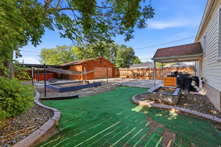 Spacious backyard featuring a large concrete patio, an open-sided covered patio, and extra wide two car garage.