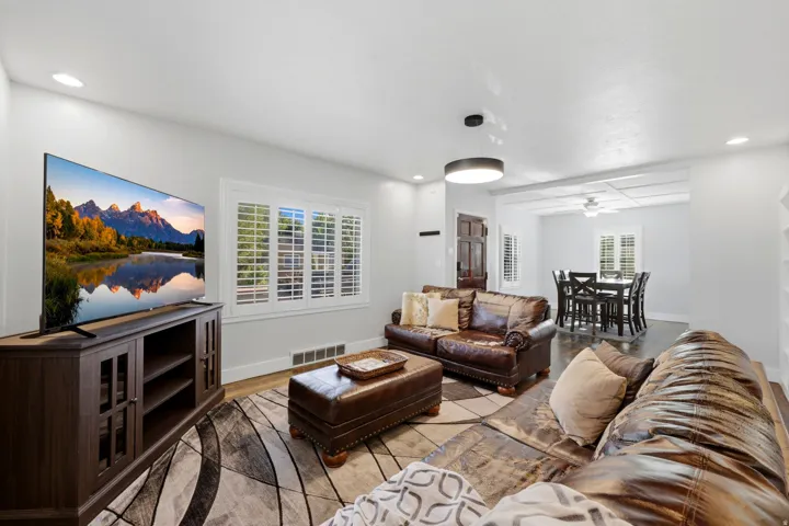Spacious living area featuring wood-finish flooring, recessed lighting, and white plantation shutters