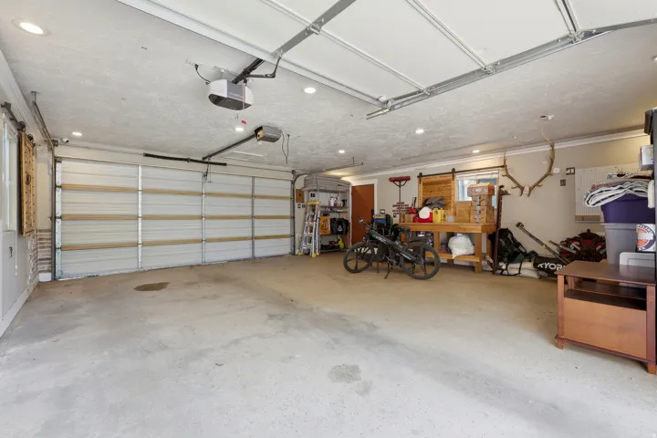 Spacious two-car garage featuring a concrete floor, recessed ceiling lighting, and two automatic garage door openers