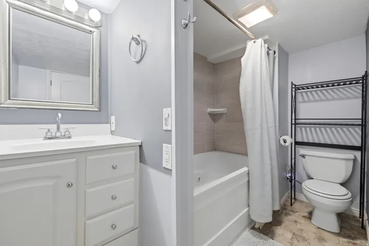 Full bathroom featuring a white vanity with integrated sink, chrome faucet, and framed mirror