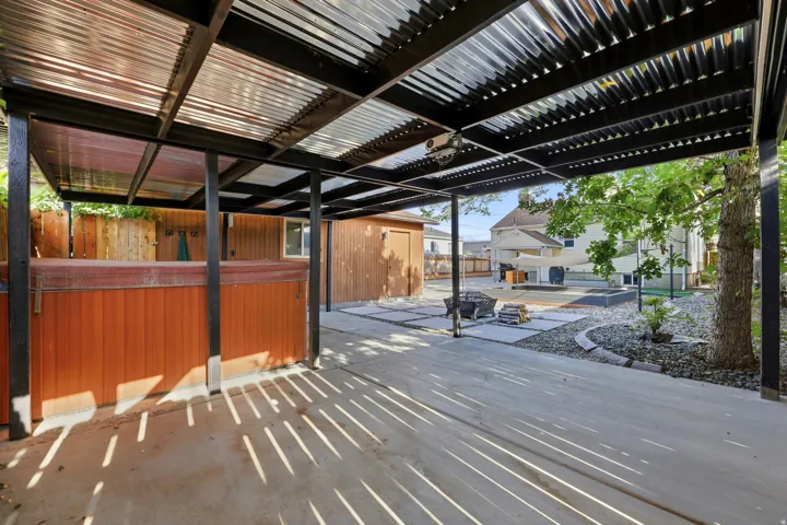 Covered outdoor patio area featuring a corrugated metal roof, integrated lighting, and concrete flooring