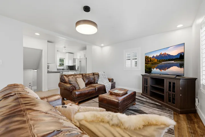 Living area with wood-finish flooring, recessed lighting, and a modern ceiling light fixture