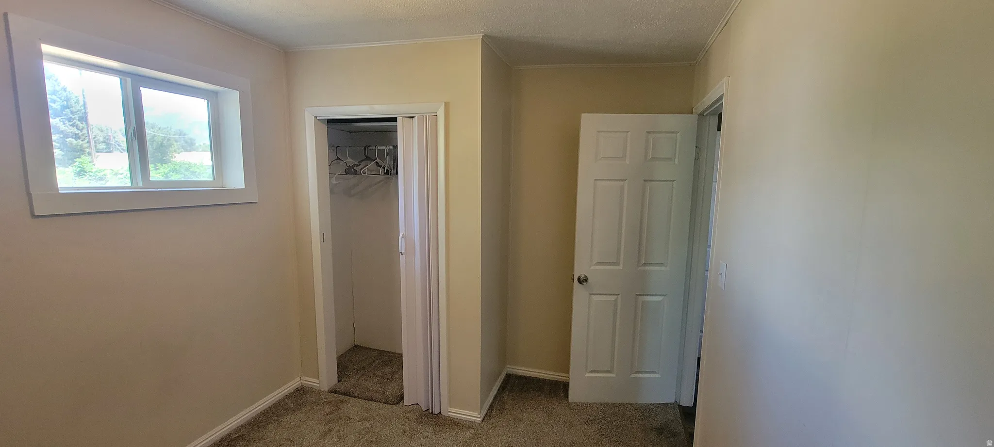 Interior space featuring neutral wall paint, a window with exterior views, a closet with bi-fold doors, and a paneled interior door
