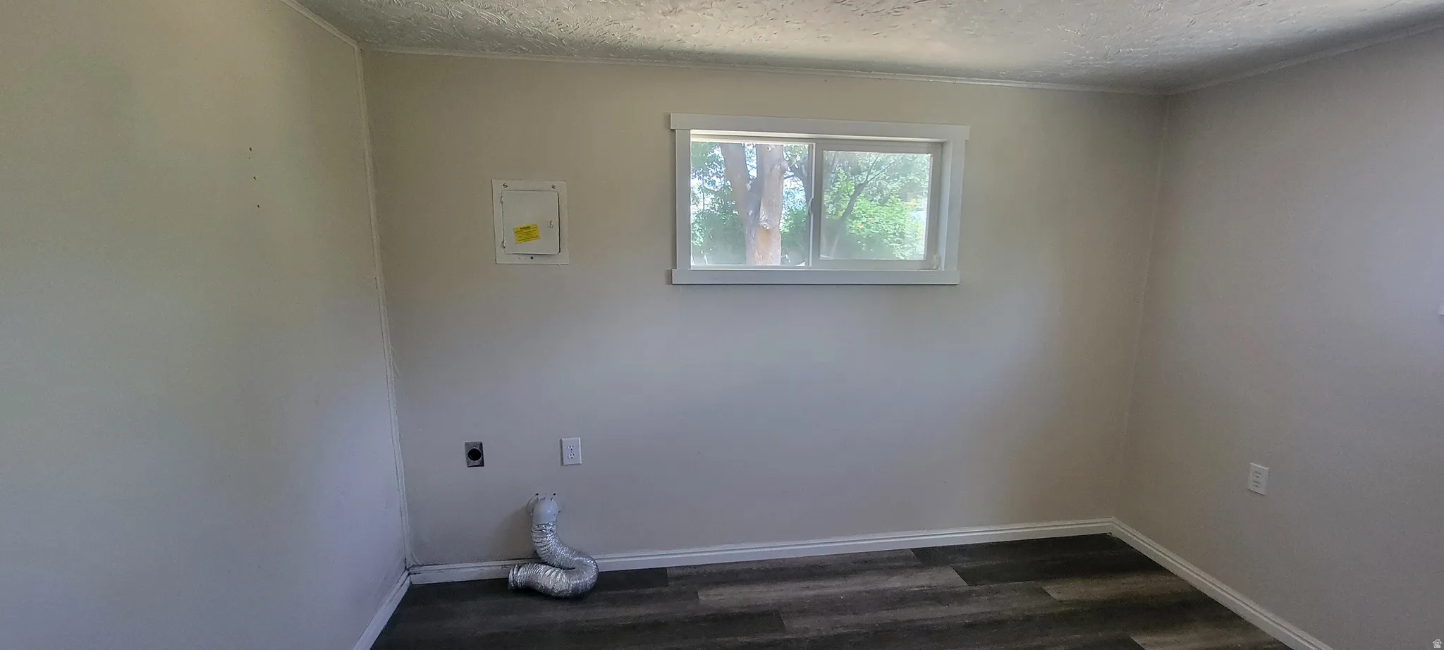Room featuring wood-finish flooring, light-toned walls, and a white-framed window