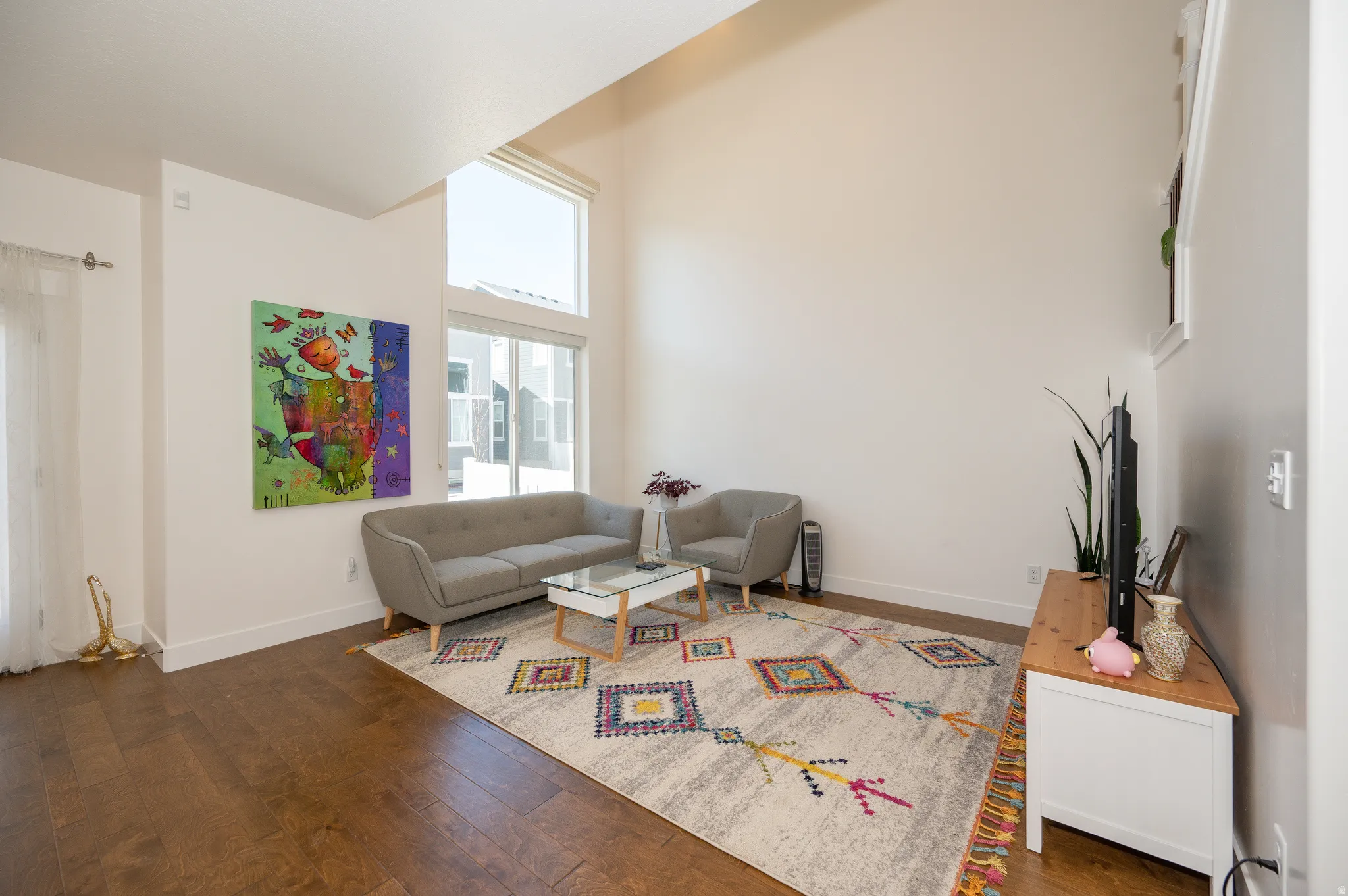 Living area featuring soaring ceilings, hardwood-finish flooring, and abundant natural light from tall windows