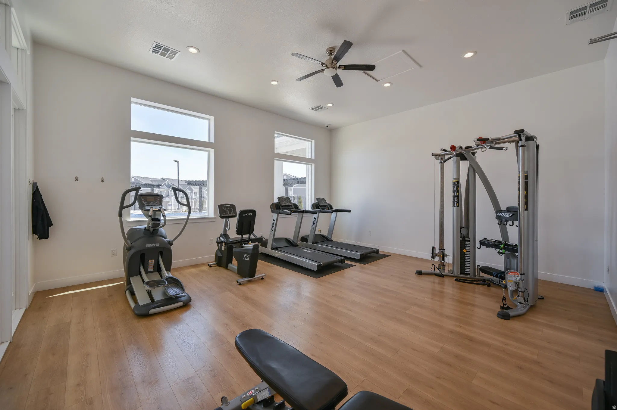 Dedicated fitness space featuring wood-finish flooring and abundant natural light from multiple windows