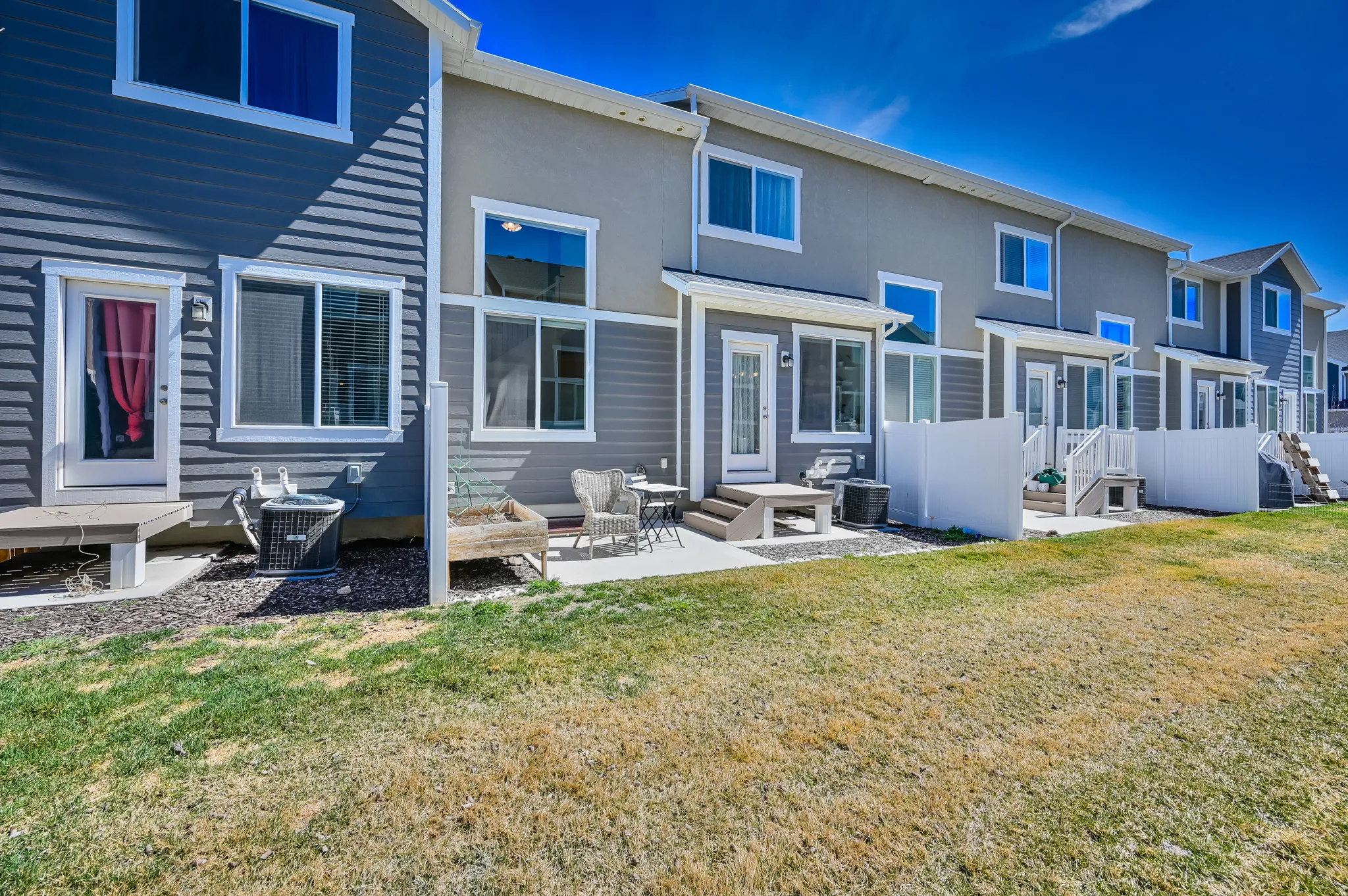 Rear exterior featuring a concrete patio, white privacy fences, and multiple large windows