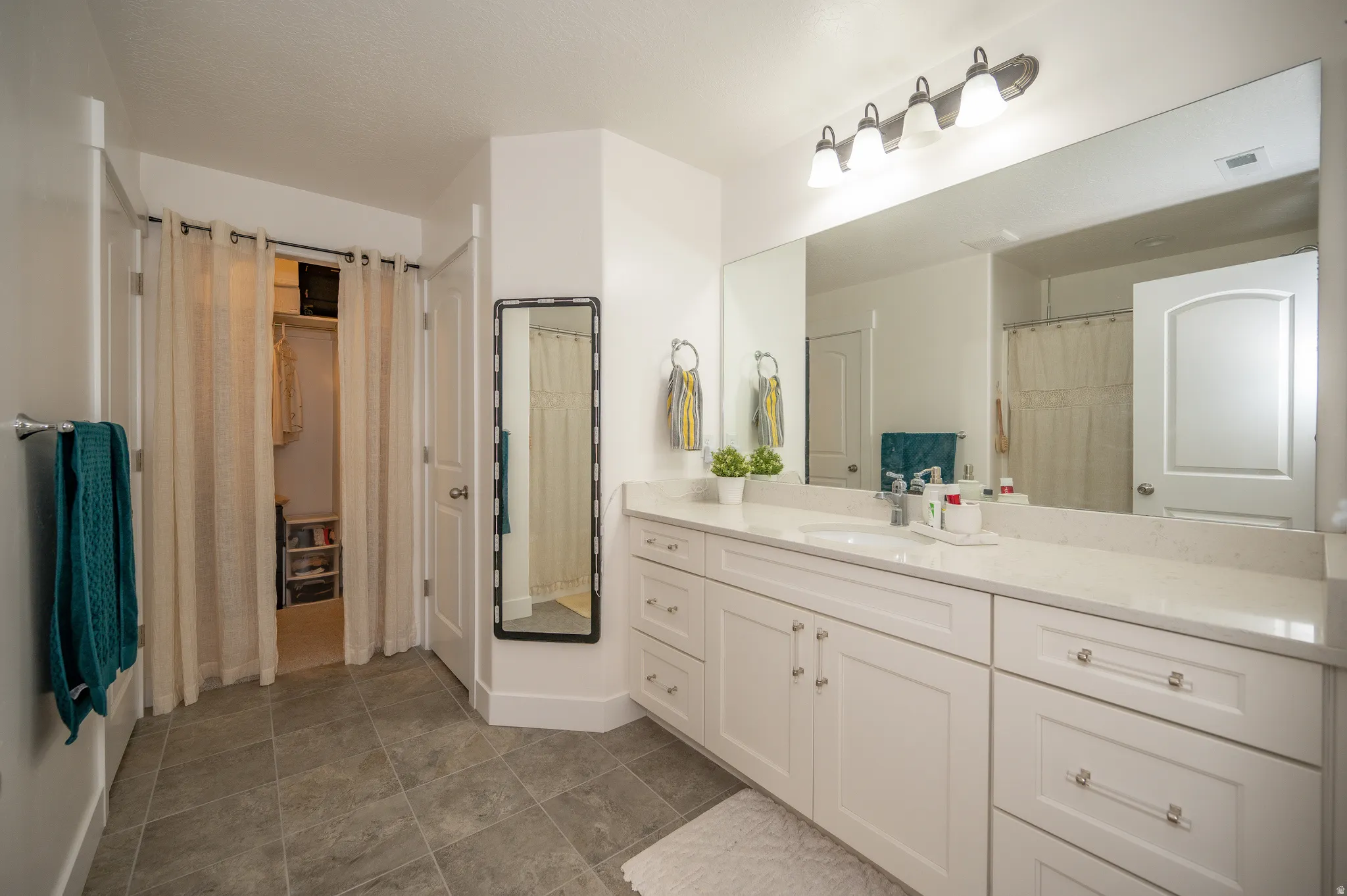 Spacious bathroom featuring an extended double vanity with white cabinetry and a light-toned countertop