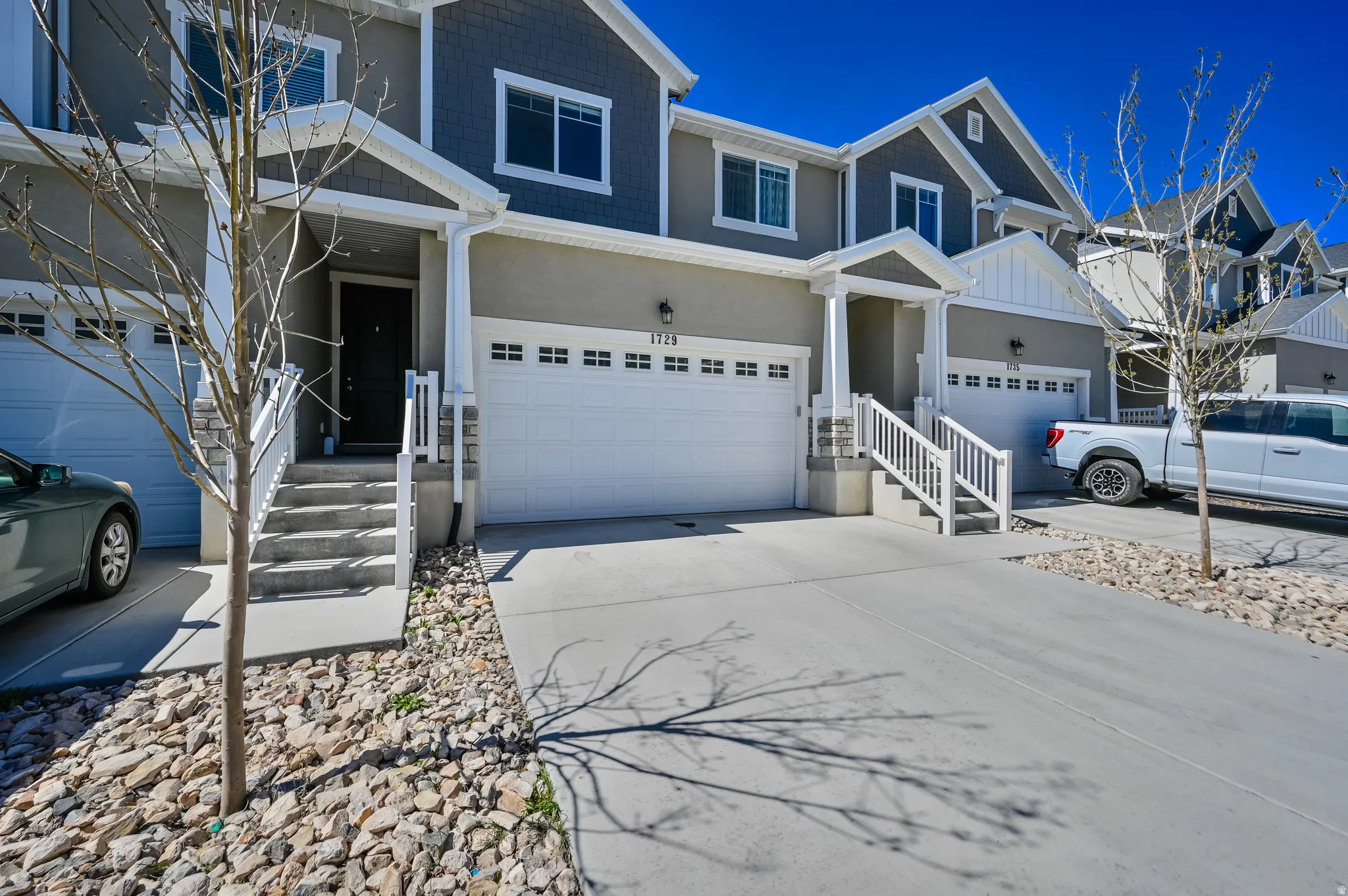 Modern townhome exterior featuring an attached garage, covered entryway, concrete driveway, and stone accents